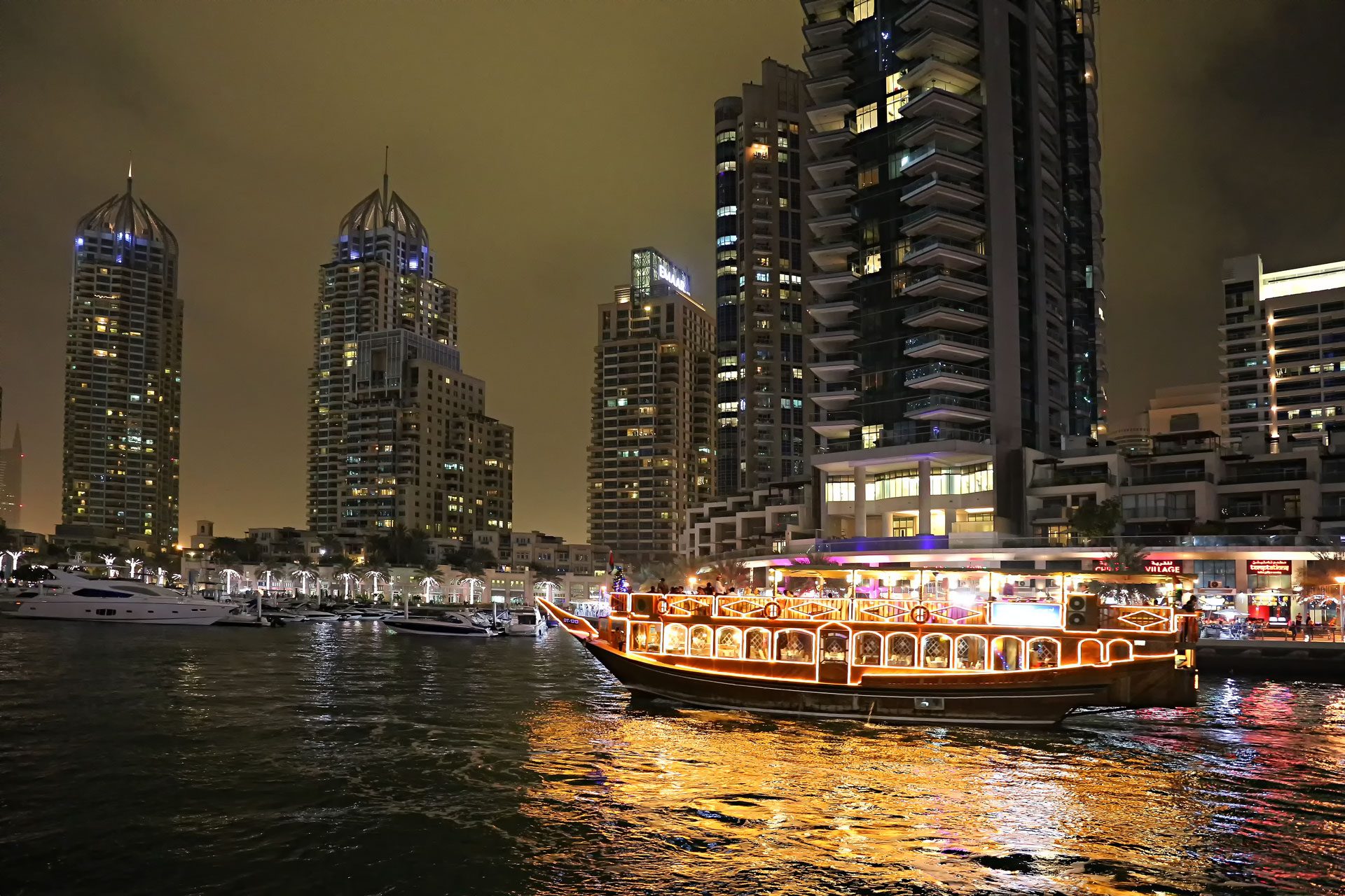 Un dhow iluminado navega por Dubai Marina de noche