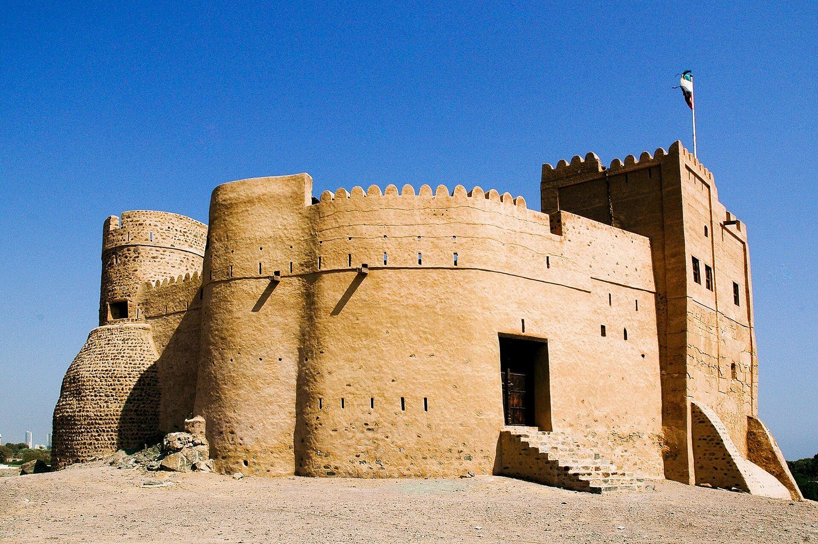 Las torres y murallas restauradas del Fuerte de Fujairah bajo un cielo azul intenso