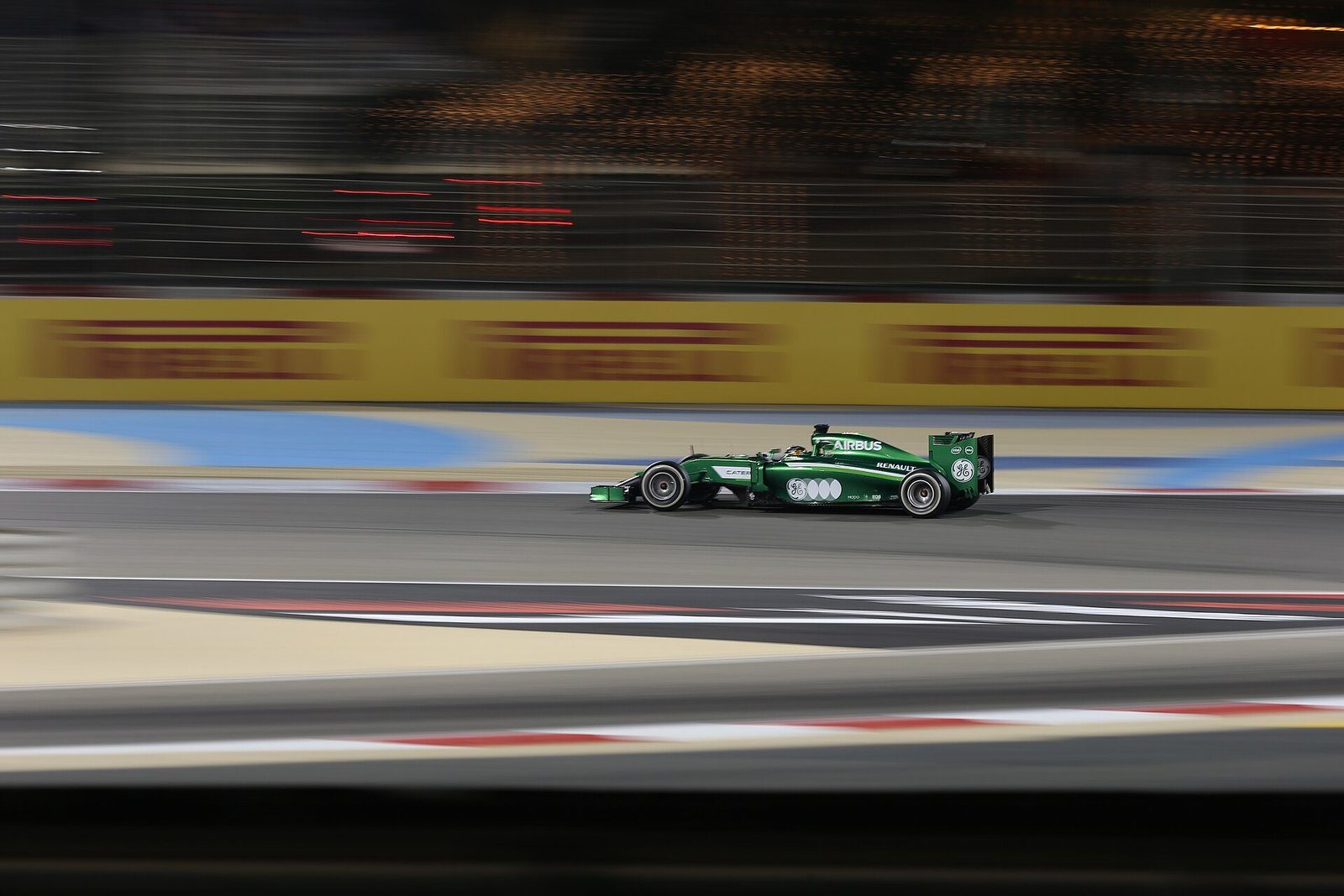 Un Fórmula 1 pasando a toda velocidad junto a las barreras de la pista bajo los focos del Bahrain International Circuit.