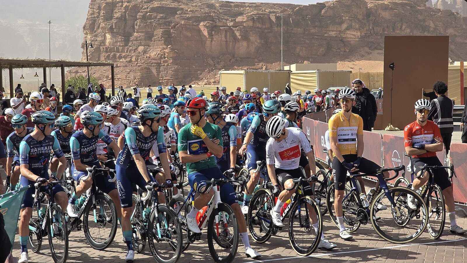 El pelotón reunido en la salida de una etapa del AlUla Tour, bajo los acantilados de arenisca de AlUla.
