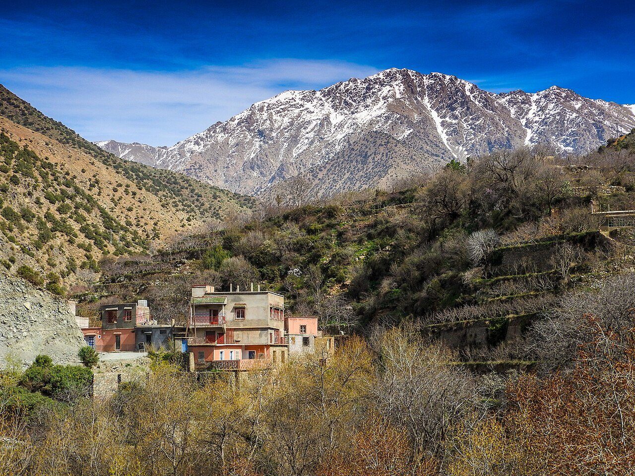 Una aldea en la ladera del valle de Ourika, bajo una cumbre nevada del Alto Atlas, Marruecos.