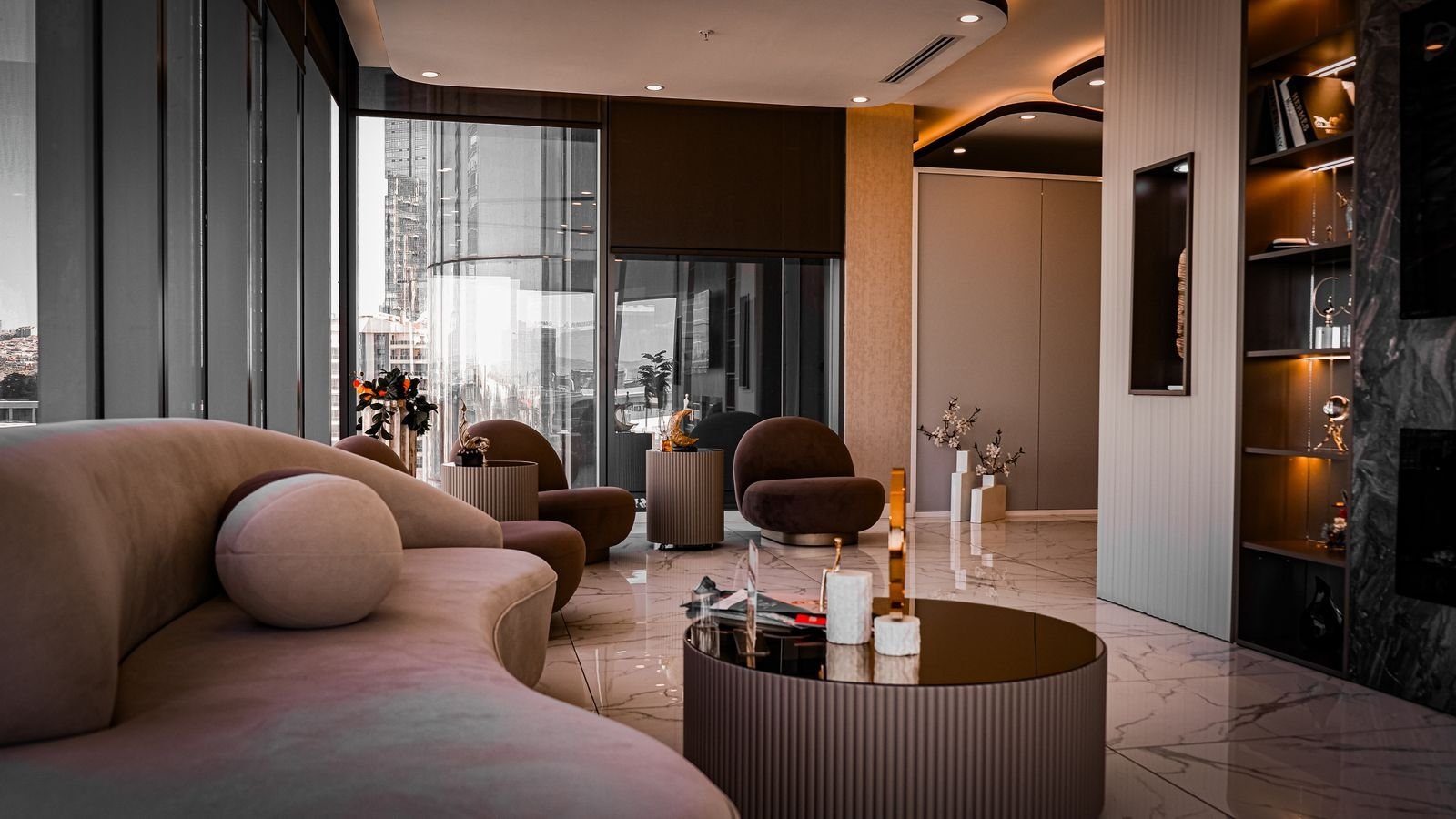 Un salón privado con sofás curvos de terciopelo, luz tenue y altos ventanales sobre la ciudad