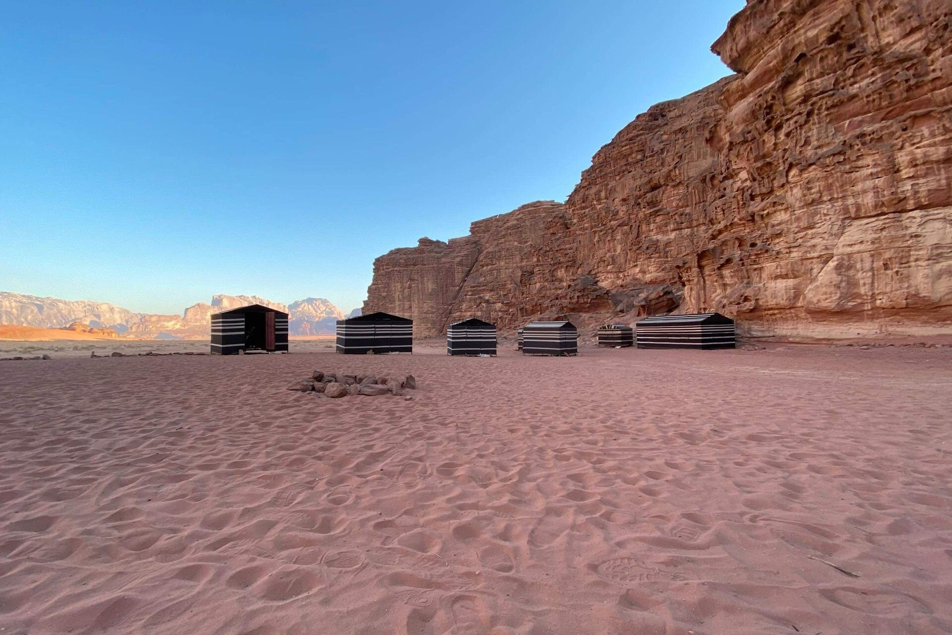 Tiendas beduinas a rayas al pie de un acantilado de arenisca en Wadi Rum, Jordania