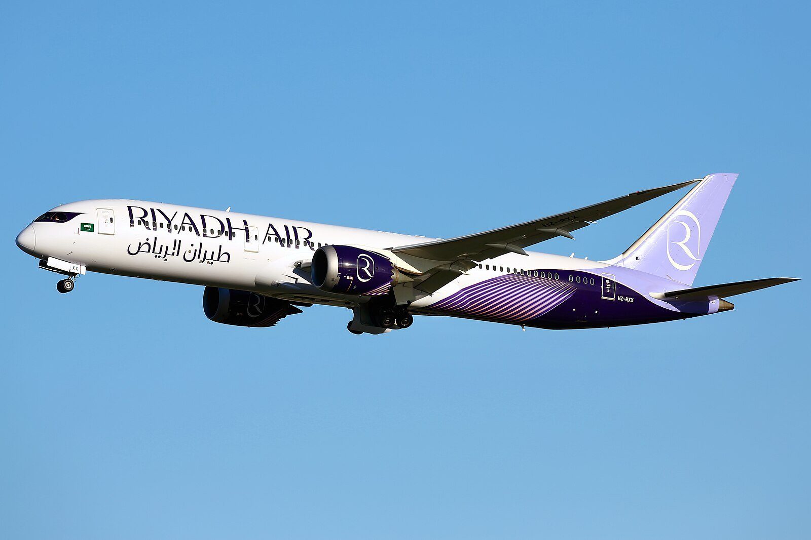 Un Boeing 787-9 Dreamliner de Riyadh Air con su librea lavanda y blanca ascendiendo hacia un cielo azul despejado.