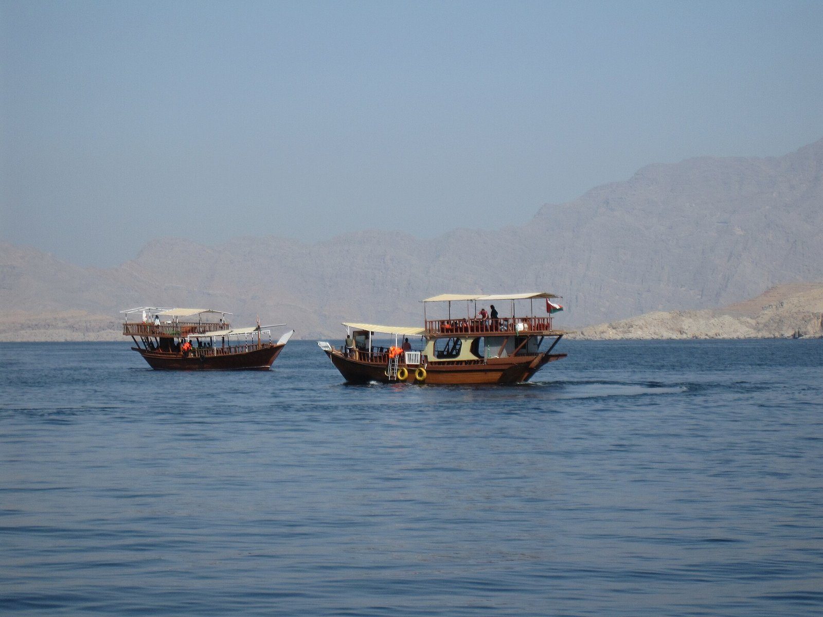 Dhows tradicionales que navegan por las aguas serenas de los fiordos de Musandam, Omán