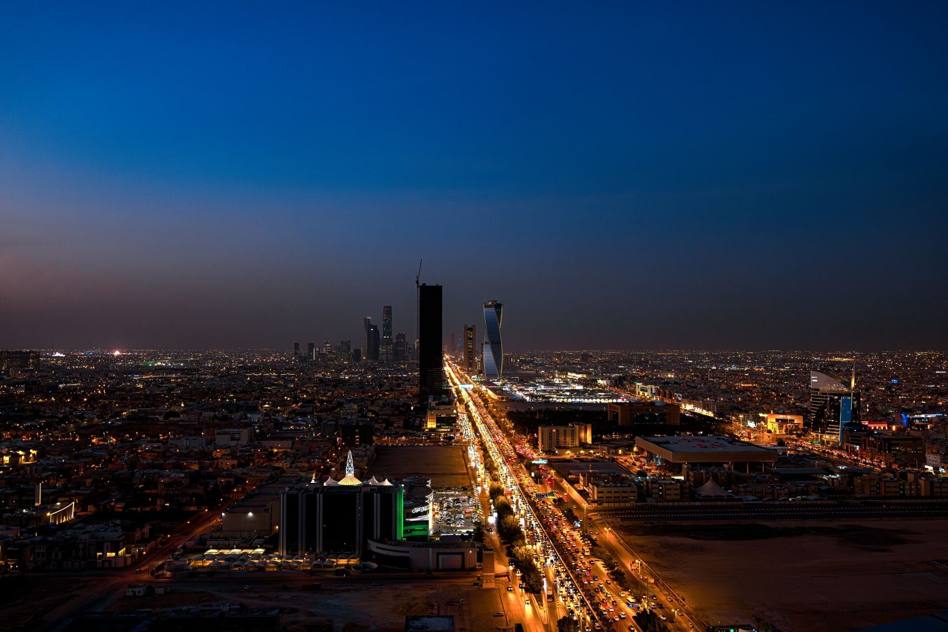 Riad al anochecer desde lo alto, con King Fahd Road avanzando hacia las nuevas torres de la ciudad