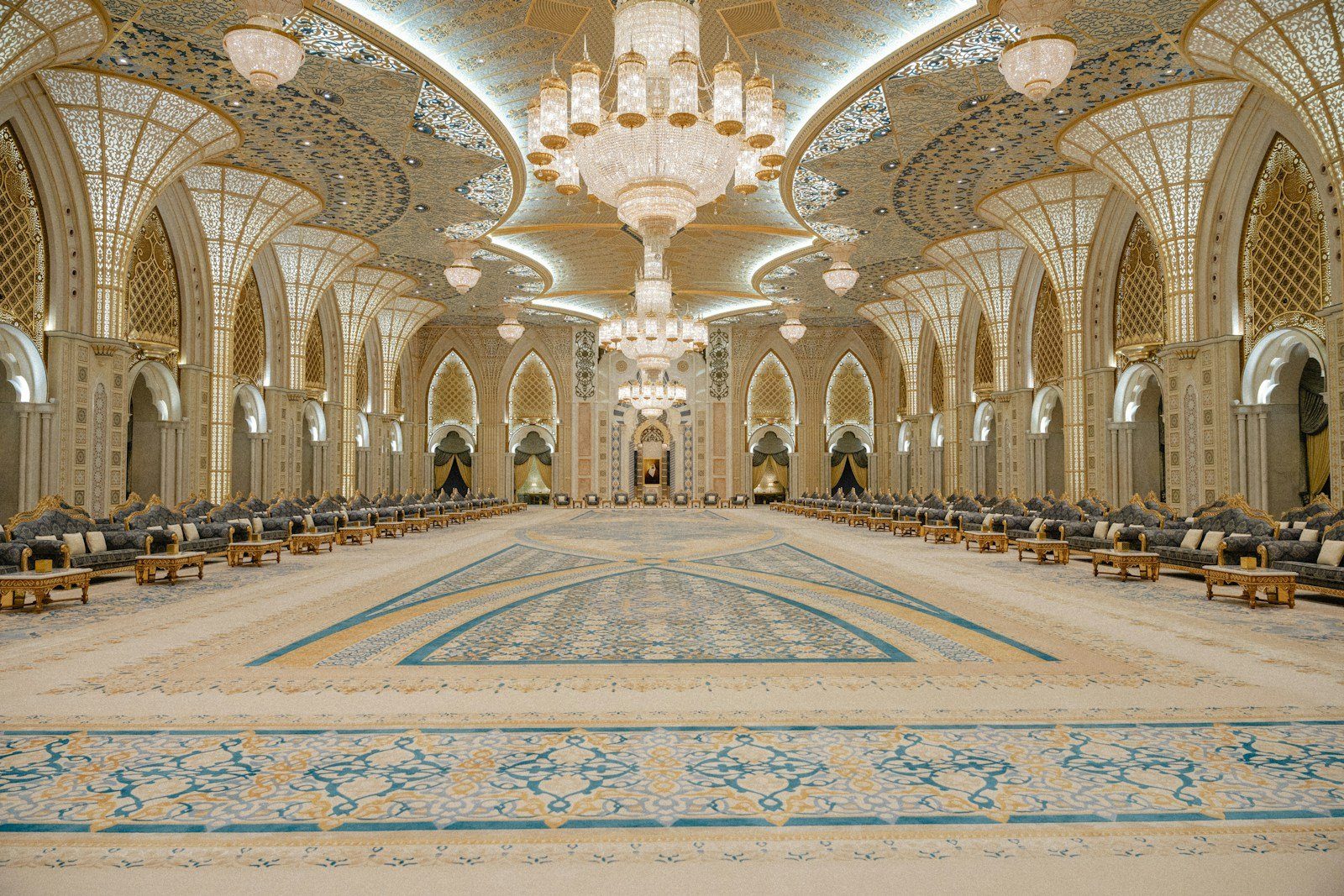 Una lámpara de araña de cristal sobre las alfombras estampadas y los arcos dorados tallados de un gran salón de Qasr Al Watan, Abu Dabi.