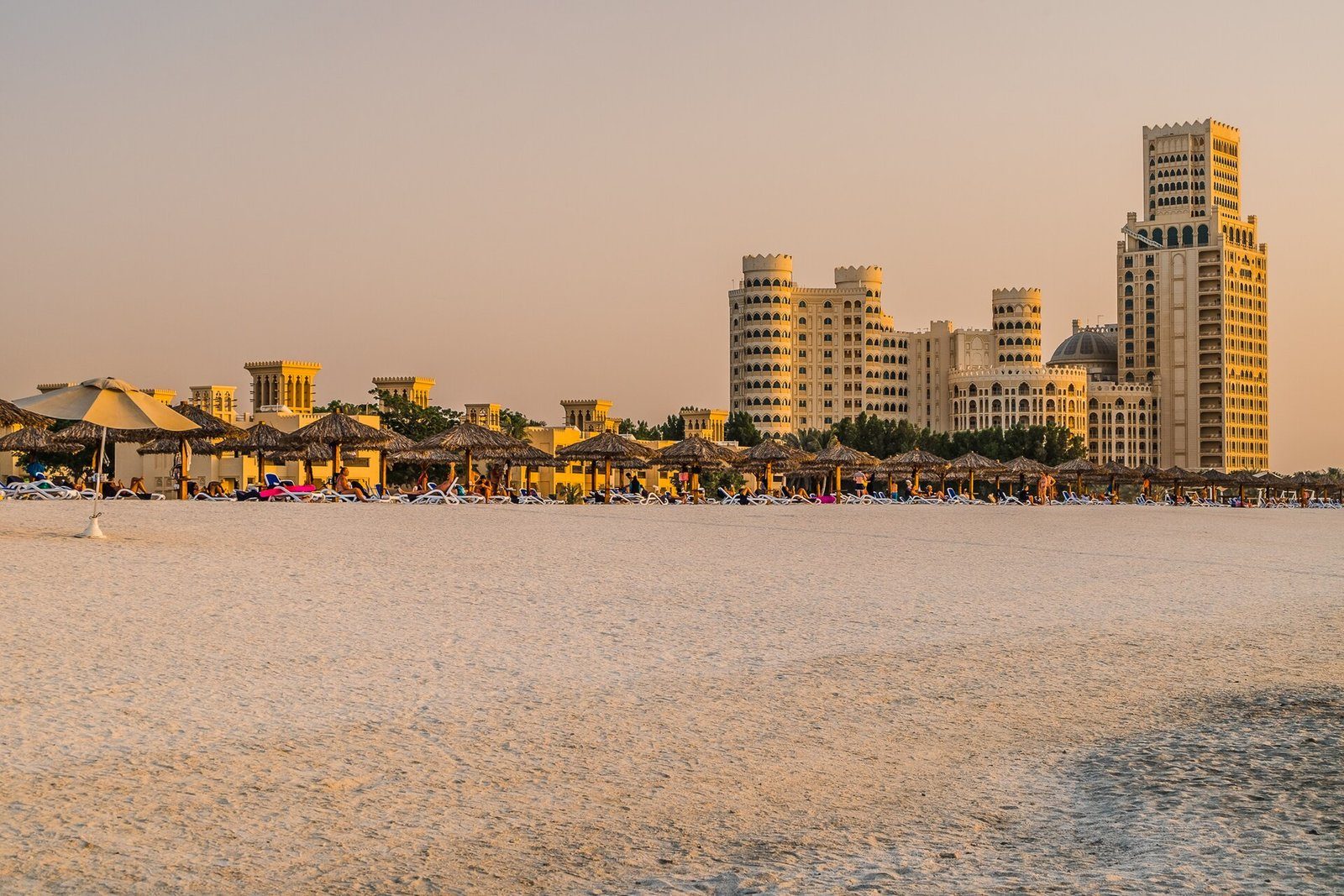 La playa de Al Hamra Village en Ras Al Khaimah en la hora dorada, con el Waldorf Astoria más allá de las sombrillas