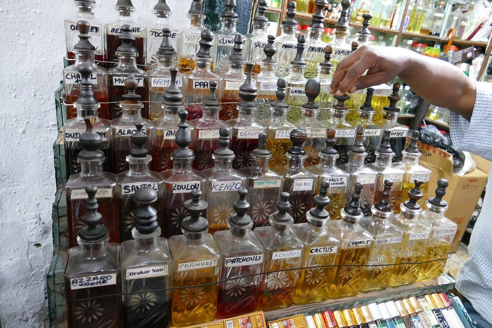 Hileras de licoreras de cristal tallado llenas de aceites de perfume ámbar en una perfumería tradicional del zoco.