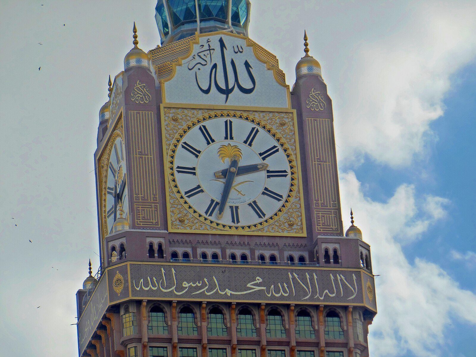 La esfera dorada y la caligrafía que coronan la Torre del Reloj Real de La Meca, en Abraj Al Bait, contra un cielo azul.