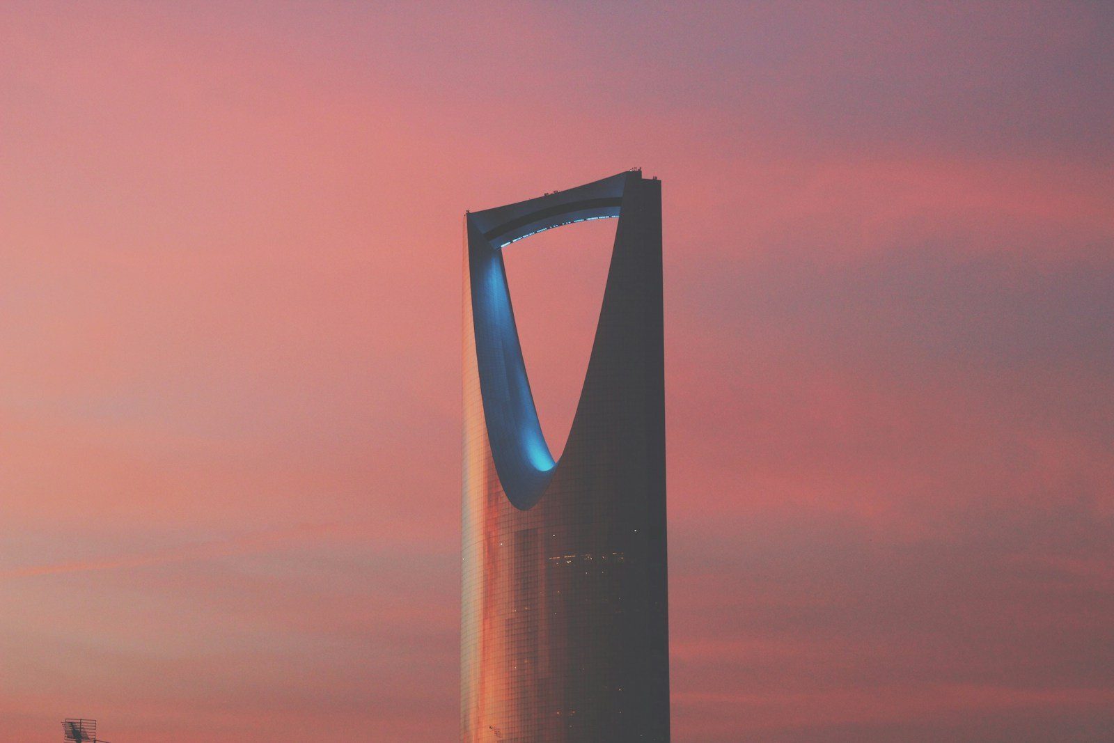 La torre del Kingdom Centre ante un cielo vespertino rosa y ámbar en Riad